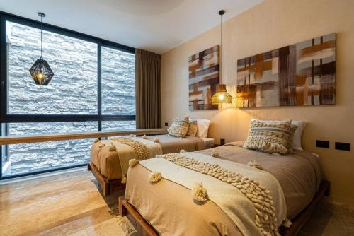two beds in a room with a large window at Luxury Beachfront 3BR Appartment in Tulum