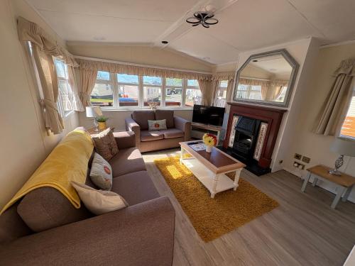 a living room with a couch and a fireplace at Cosy Caravan by the sea in Cairnryan