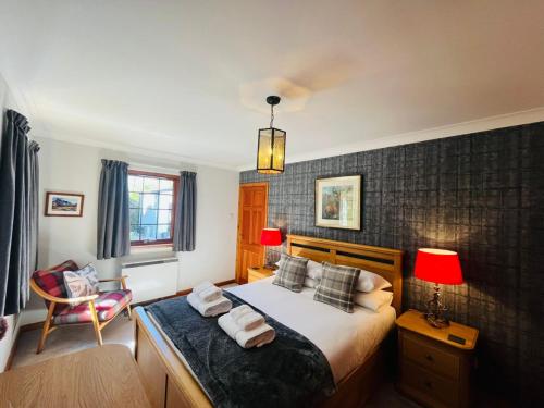a bedroom with a bed with two lamps and a chair at Braehead Cottage in Glencoe