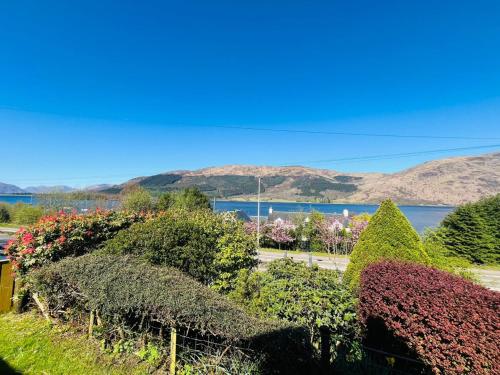 a garden with a view of the water and mountains at Braehead Cottage in Glencoe