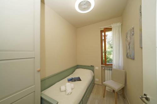 a small room with a bed and a chair at Olive Garden Garda - pool & view in Moniga