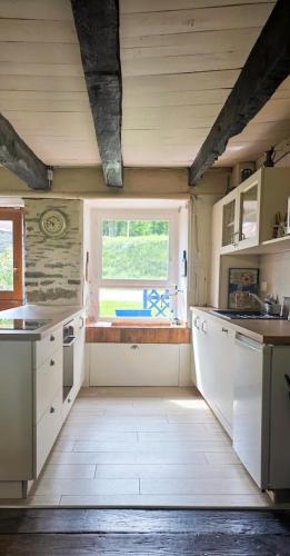 a kitchen with white cabinets and a window at Penty horizon de Brocéliande in Augan