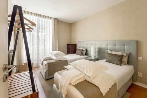 a bedroom with two beds and a large window at Casas do Porto - Ribeira Apartments in Porto