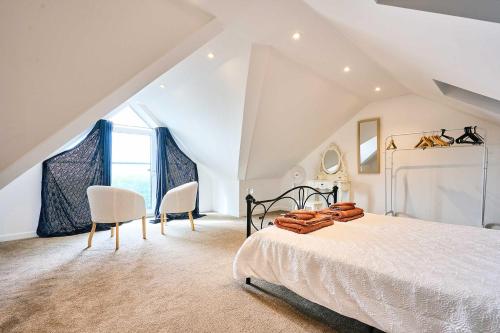 a white bedroom with a bed and two chairs at Host & Stay - 2a Hamilton Road in Felixstowe