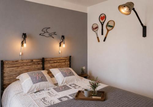 a bedroom with a bed with two tennis rackets on the wall at Domaine du Prieuré avec Piscine Ancien Couvent & Presbytère in Carcassonne