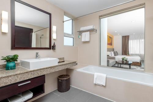 a bathroom with a tub and a sink and a mirror at Somerset Hoa Binh Hanoi in Hanoi