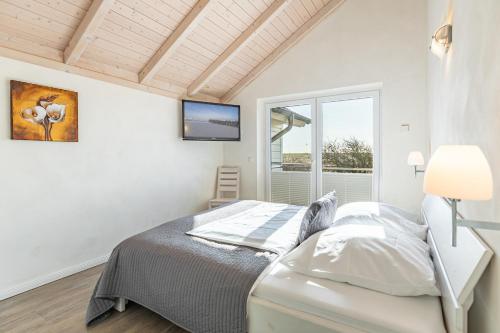 a white bedroom with a bed and a window at Ferienhaus Rotschenkel in Dagebüll