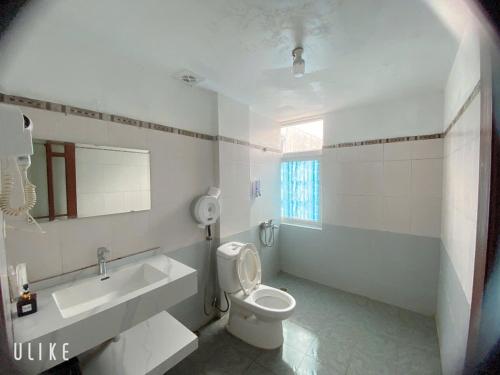 a white bathroom with a toilet and a sink at Hotel Nam Sơn in Hai Phong