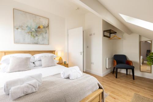 a bedroom with a white bed and a blue chair at The Wave - Room 15 in Rhosneigr