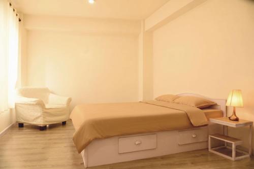 a white bedroom with a bed and a chair at BasantapurRooms in Kathmandu