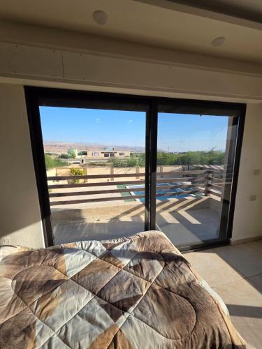 a bedroom with a bed and a large glass window at Green view in Al Mazār
