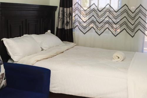 a bed with white sheets and pillows next to a window at The Quiet Nest in Ruiru