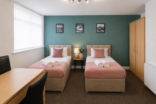 a room with two beds and a table and a desk at Spacious, Modern and stylish three bedroom home , perfect for work , leisure and contractors ,5 mins walk to Newcastle city Center, Newcastle stadium and Newcastle University, Free parking Fast WiFi, conveniently located both short stay and long stays in Newcastle upon Tyne