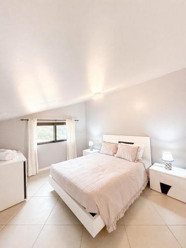 a white bedroom with a large bed and a window at Vista Sol in Bicas