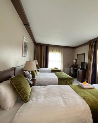 a hotel room with three beds and a window at Woodford Dolmen Hotel Carlow in Carlow