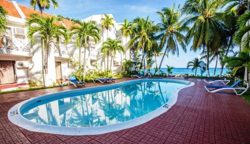 a swimming pool in front of a building with palm trees at Idyllic Beachfront Condo in Ocho Rios