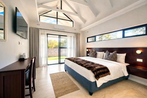 a bedroom with a bed and a desk and windows at 19 On Bay Noakes in Harare