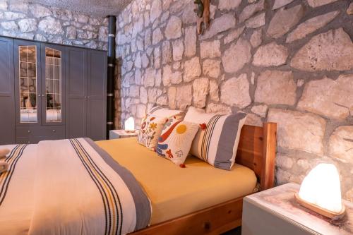 a bed in a room with a stone wall at Kösedere Stone Houses in Karaburun