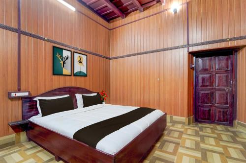 a bedroom with a large bed and a wooden wall at Hotel O Kallar Vattiyar Waterfalls Munnar in Munnar