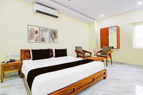 a bedroom with a large bed and two chairs at Super OYO Townhouse Dwarakanagar Near Gurudwara in Visakhapatnam