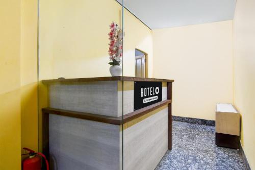 a reception desk with a vase of flowers on it at Hotel O Ecopark Kolkata in kolkata