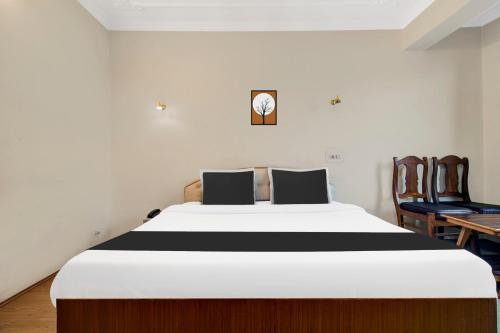 a bedroom with a large white bed and two chairs at Super Townhouse Rajbagh Formerly Hotel Modern in Srinagar