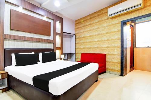 a bedroom with a bed and a red chair at Collection O Karaya Road Formerly Hotel New Diamond in Kolkata