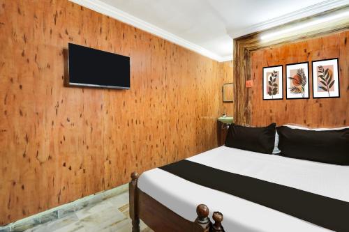 a bedroom with a wooden wall with a bed and a tv at Super Hotel O Chowrasta Near Congress Bhavan in Warangal
