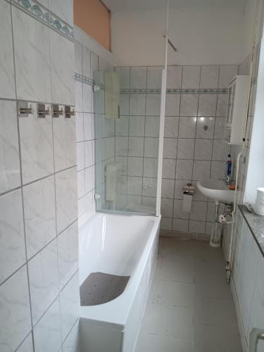 a white bathroom with a tub and a sink at Gemütliche Ferienwohnung in Bottrop