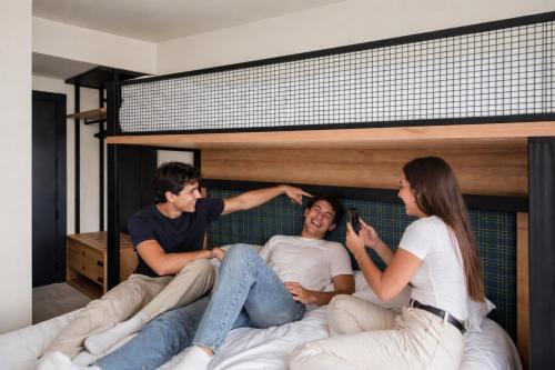 a group of three people sitting on a bed at LATROUPE La Granja in Bilbao