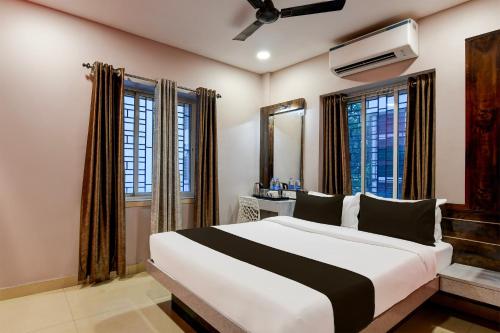 a bedroom with a large white bed with windows at Super Collection O New Town Near OM Sweets Formerly Shiva Inn in kolkata