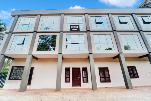a large white building with a sign on it at Super Hotel O Sultan Bathery Formerly Bluevalley in Wayanad