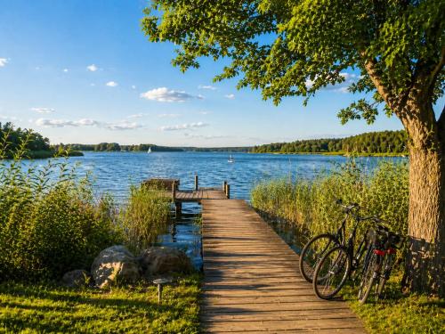 a wooden path to a lake with bikes parked on it at Ferienhaus Seerose - Sauna, eingezäunter Garten, Hunde, 3 min zum See in Göhren-Lebbin