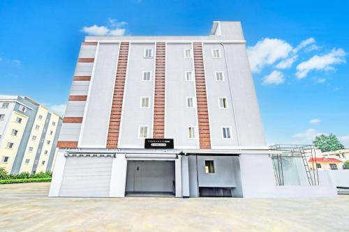 a large white building with two garage buildings at Super Townhouse Oak Kompally in Hyderabad