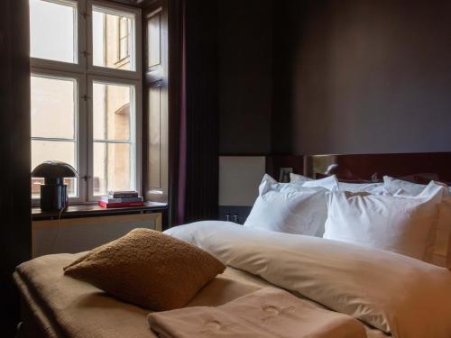 a bedroom with a bed with white pillows and a window at Four Suites Copenhagen - Boutique Townhouse Suites in Copenhagen