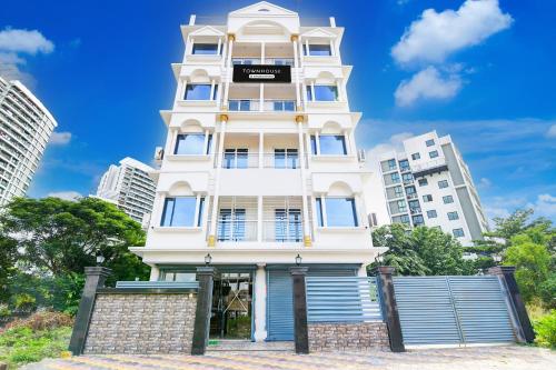 a tall white building in front of tall buildings at Super Townhouse Rosedale Formerly Reliance Guest House in Kolkata