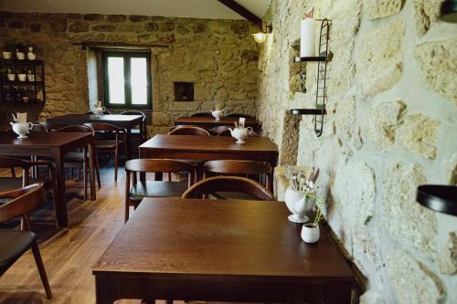 a restaurant with wooden tables and chairs and a brick wall at Casa d'Amares in Amares