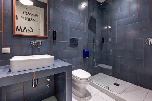a blue tiled bathroom with a toilet and a sink at Colors Urban Hotel Thessaloniki in Thessaloniki