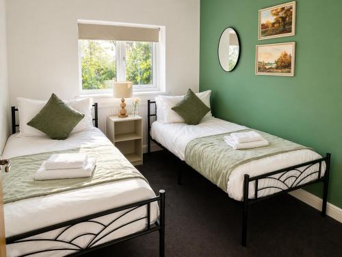 two beds in a room with green walls at 4 Bedroom House Coventry Sleep 7 with 3 Parking Spaces in Coventry