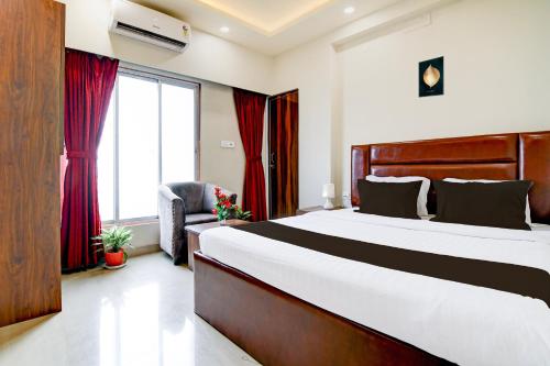 a bedroom with a large bed and a chair at Super Townhouse Kaikhali Near Airport in Kolkata