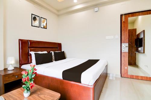 a bedroom with a bed and a table and a mirror at Super Townhouse Kaikhali Near Airport in Kolkata