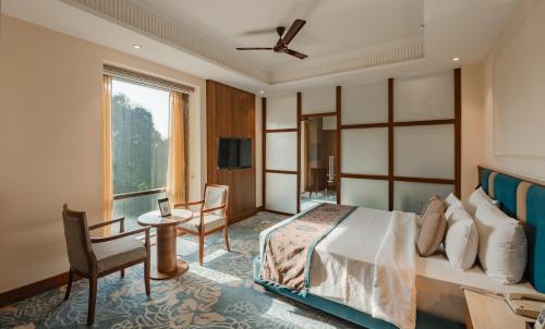a bedroom with a bed and a table and a window at The India Benares in Varanasi