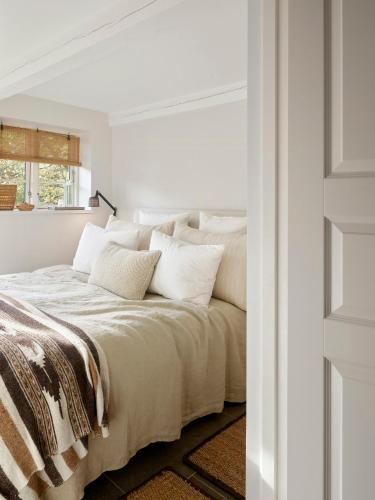 a white bedroom with a large bed with white pillows at Historic Vipp House From 1775 In Søllested in Søllested