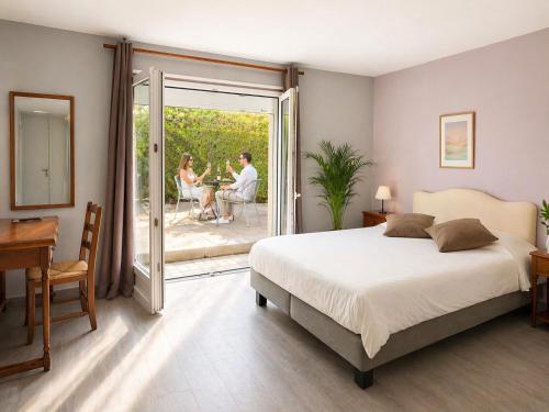a bedroom with a bed and people sitting on a patio at Le Clos De Mutigny in La Chaussée-sur-Marne