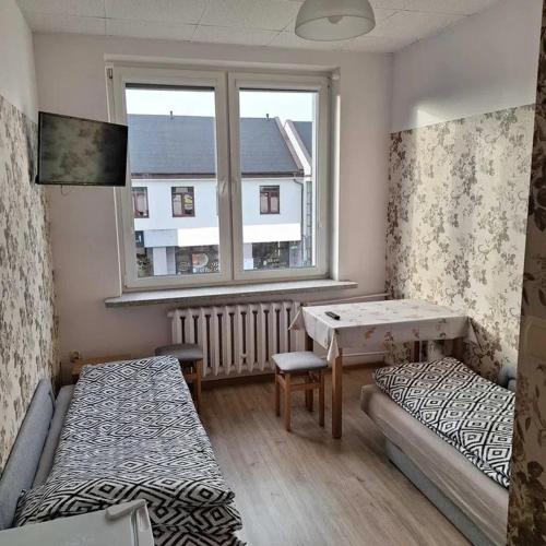 a room with two beds and a table and a window at Hostel Włocławek in Włocławek