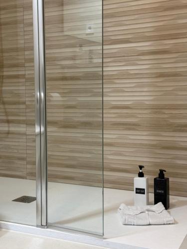 a shower with a glass door and a bottle of soap at Apartamentos Salceda in Noja
