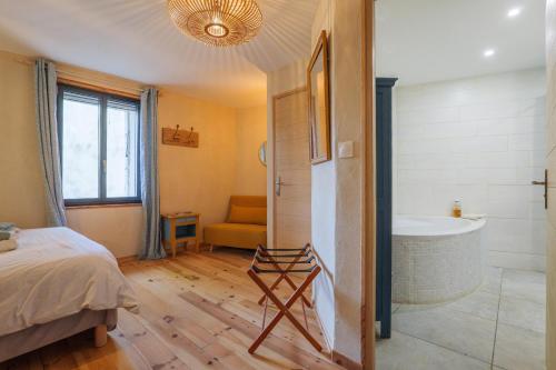 a bedroom with a tub and a bed and a bathroom at Chambres D’hôtes - Les Agrions in Saint-Remèze