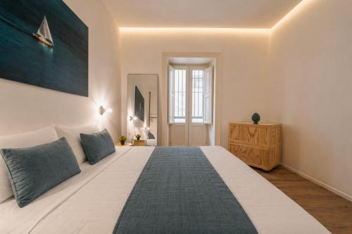a bedroom with a large white bed with blue pillows at Palazzo Lucatelli Suite - Centro in Trapani