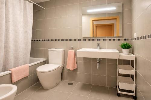 a bathroom with a toilet and a sink and a mirror at Apto Llanes Bajo con terraza - Casa Juanín in Llanes