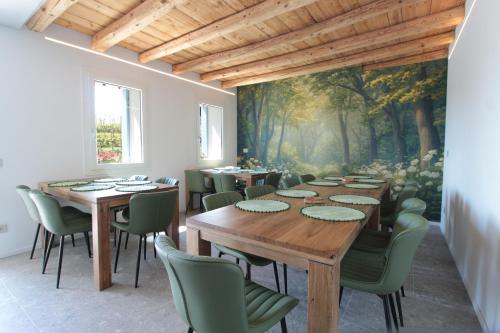 a dining room with wooden tables and green chairs at Villa Valdobbiadene Pool Spa in Valdobbiadene